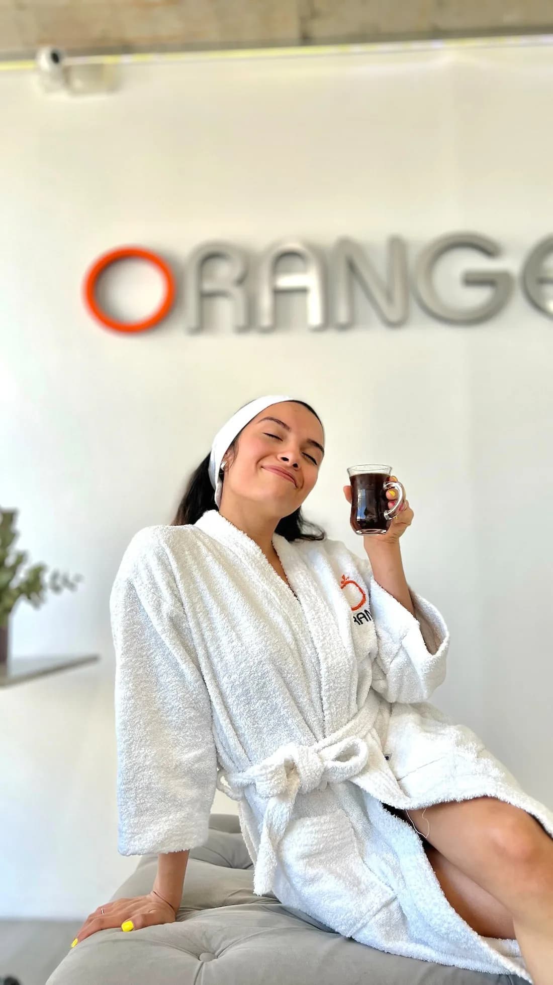 Una mujer con bata de Orange disfrutando una bebida en el centro