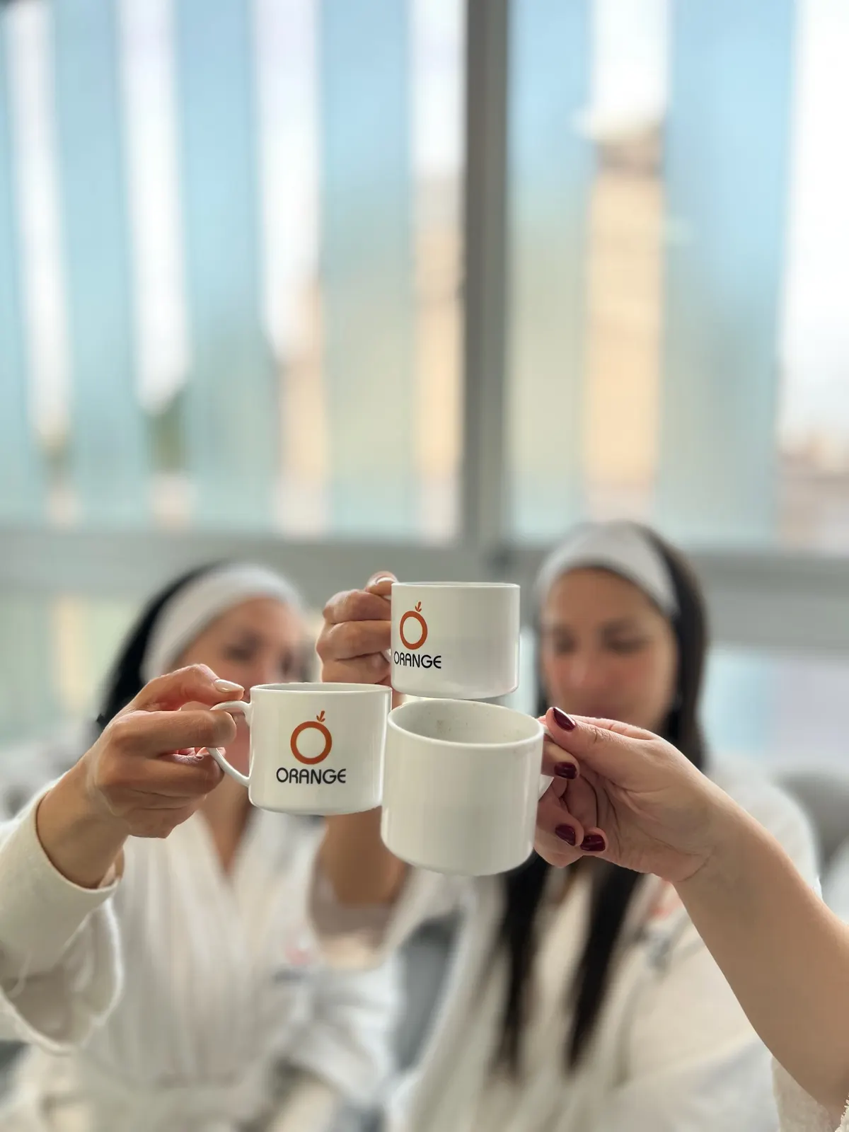 Clientas con batas de Orange brindando con tazas del centro